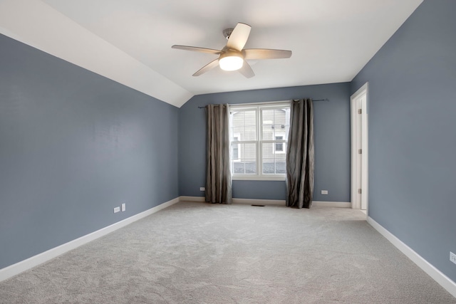 spare room with carpet, a ceiling fan, baseboards, visible vents, and vaulted ceiling