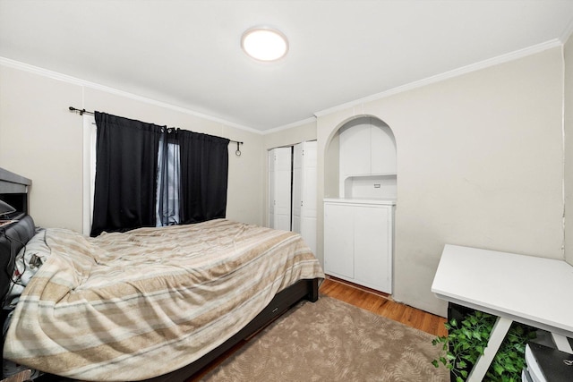 bedroom with ornamental molding, light wood finished floors, a closet, and arched walkways