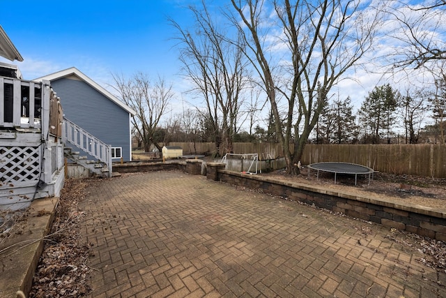 view of patio / terrace with a trampoline, fence, and stairway