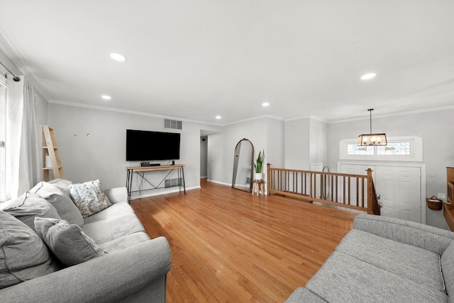 living room featuring ornamental molding, light wood-type flooring, visible vents, and recessed lighting