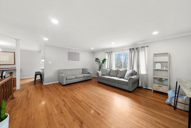 living area featuring recessed lighting, baseboards, ornamental molding, light wood finished floors, and ornate columns