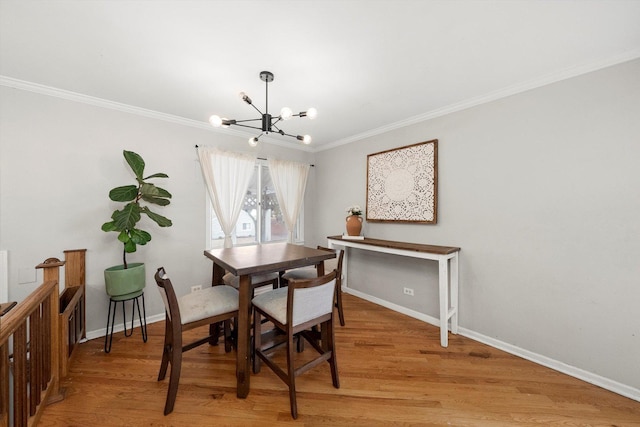 dining area with baseboards, light wood-style floors, crown molding, and a notable chandelier