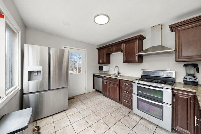 kitchen with stainless steel appliances, dark brown cabinets, wall chimney exhaust hood, and a sink