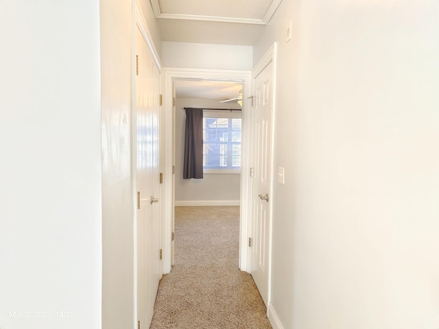 corridor with carpet floors, baseboards, and crown molding