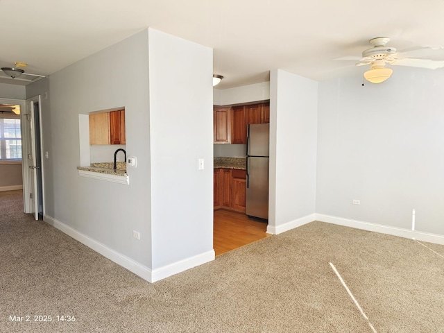 interior space with light carpet, ceiling fan, and baseboards