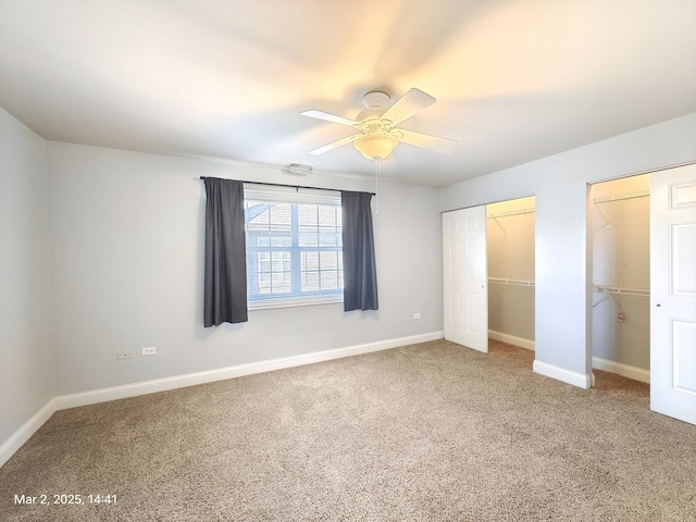 unfurnished bedroom featuring multiple closets, visible vents, carpet flooring, ceiling fan, and baseboards