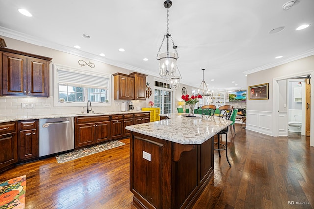 kitchen featuring dark wood-style floors, a kitchen island, a sink, dishwasher, and a kitchen breakfast bar