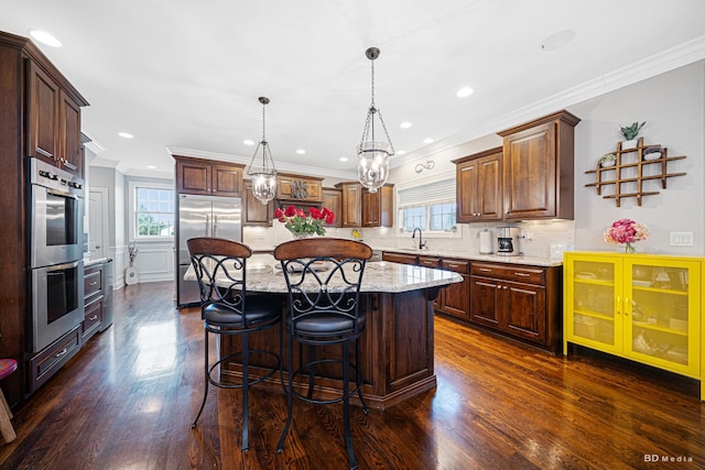 kitchen featuring a healthy amount of sunlight, a kitchen breakfast bar, stainless steel appliances, and a sink