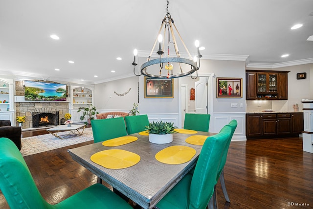 dining area with dark wood-style floors, built in features, a fireplace, and ornamental molding