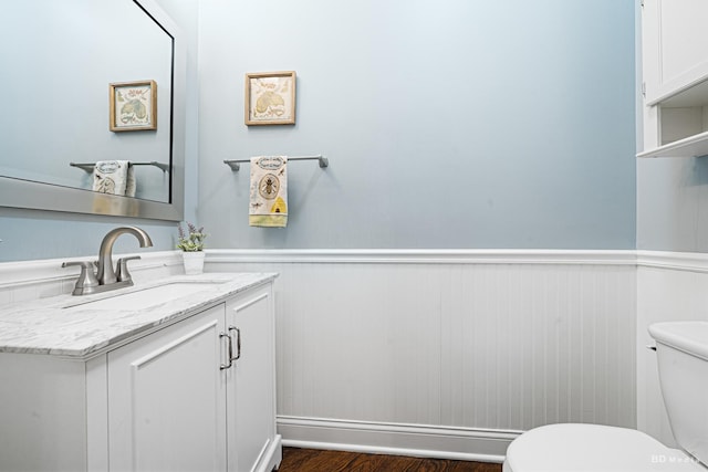 bathroom with a wainscoted wall, toilet, and vanity