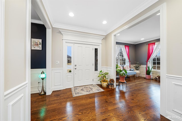 entrance foyer featuring wood finished floors, a wainscoted wall, and ornamental molding