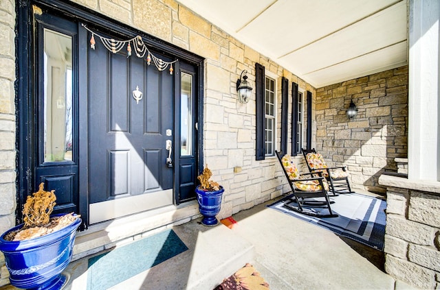 doorway to property featuring stone siding and covered porch