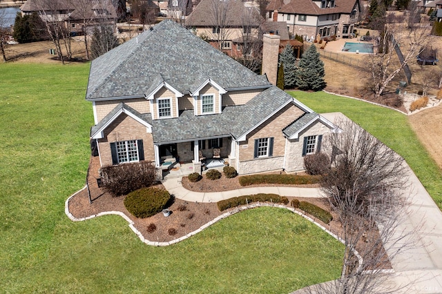 view of front facade with brick siding, a front lawn, a chimney, a patio area, and stone siding