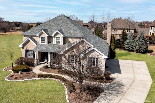 traditional home with stone siding, driveway, a front lawn, and roof with shingles