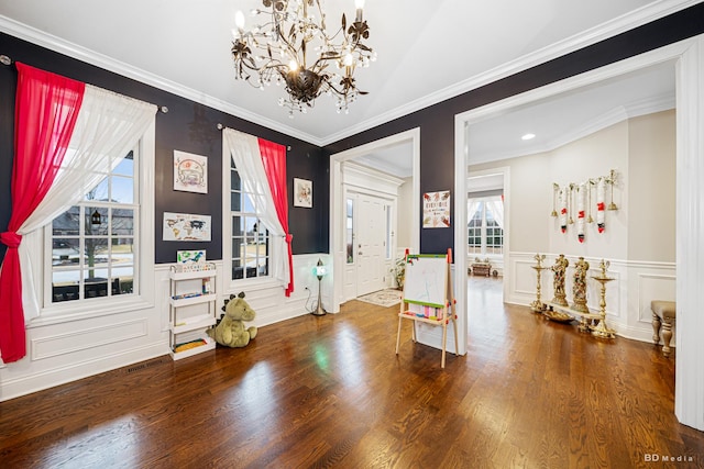 entryway featuring a notable chandelier, visible vents, crown molding, and wood finished floors