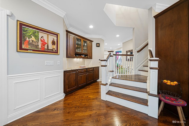 staircase featuring a wainscoted wall, crown molding, and wood finished floors