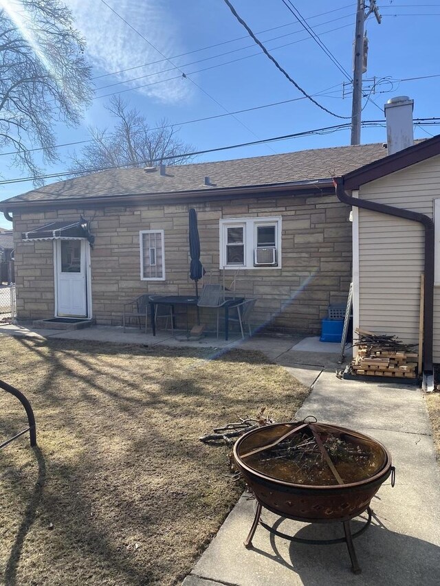 3300 N Osage Ave, Chicago, IL 60634 - rear view of property featuring an outdoor fire pit, a patio area, stone siding, and roof with shingles