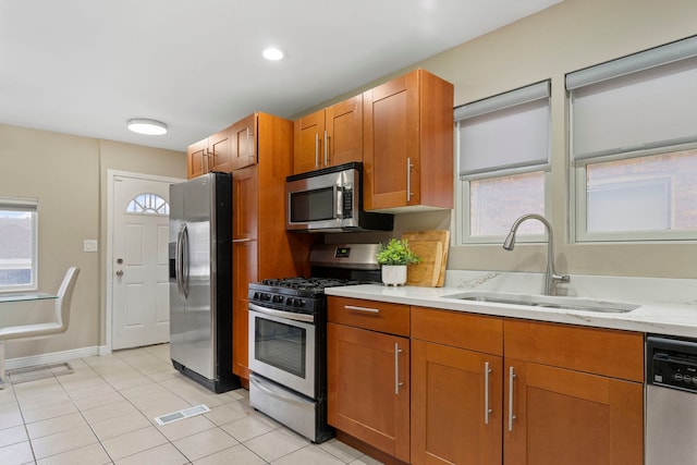 kitchen featuring a sink, a healthy amount of sunlight, brown cabinets, and stainless steel appliances