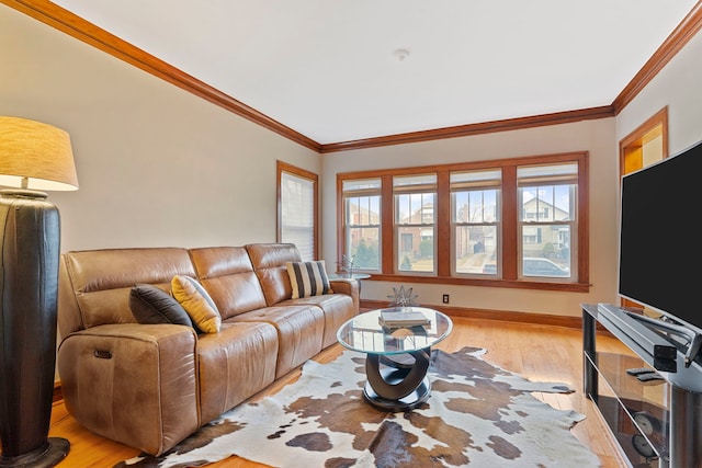 living area with baseboards, crown molding, and light wood-style floors