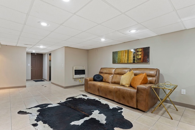 living area with heating unit, light tile patterned floors, a paneled ceiling, and baseboards