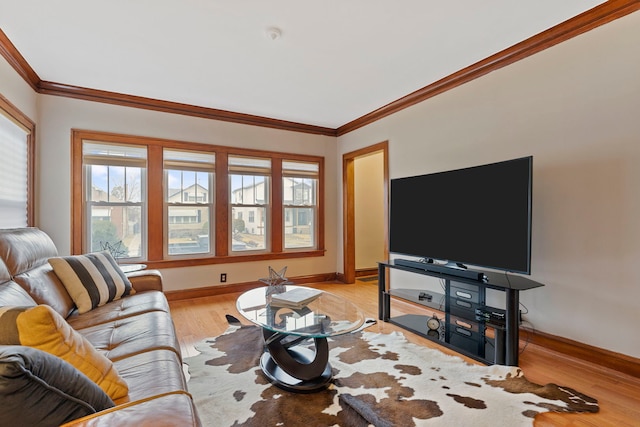 living area with baseboards, plenty of natural light, light wood-style flooring, and ornamental molding