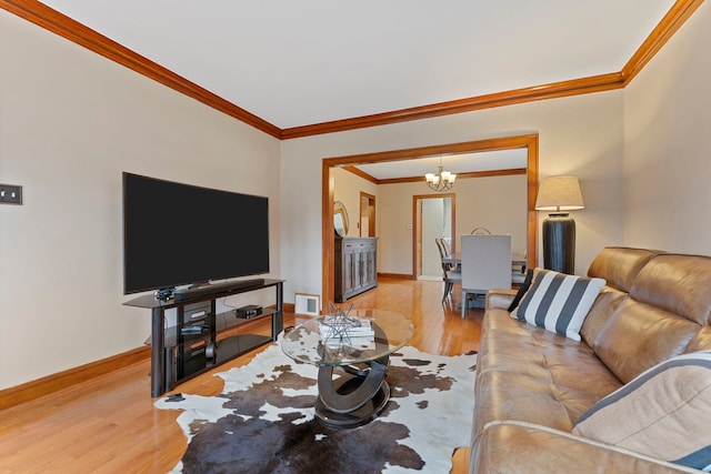 living room with visible vents, wood finished floors, crown molding, baseboards, and a chandelier