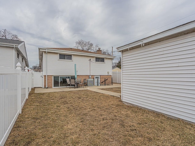 back of property with a lawn, a fenced backyard, cooling unit, a patio area, and brick siding