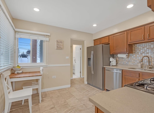 kitchen featuring light countertops, appliances with stainless steel finishes, brown cabinetry, and a sink