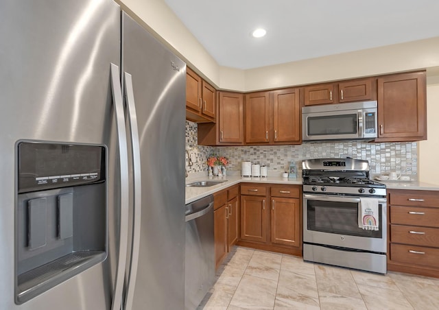 kitchen featuring decorative backsplash, appliances with stainless steel finishes, brown cabinets, light countertops, and a sink