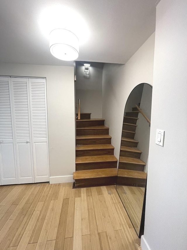 staircase with wood finished floors, baseboards, and arched walkways