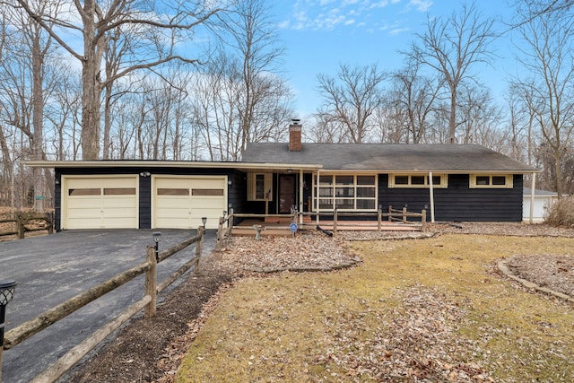 ranch-style home featuring a garage, aphalt driveway, and a chimney