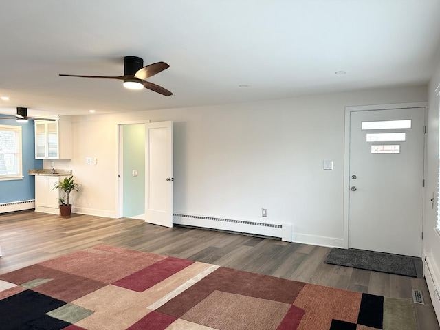 entryway with a baseboard heating unit, baseboard heating, wood finished floors, and baseboards