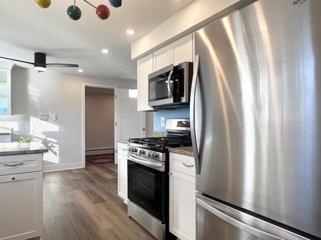 kitchen with light stone counters, recessed lighting, stainless steel appliances, dark wood-style flooring, and white cabinetry