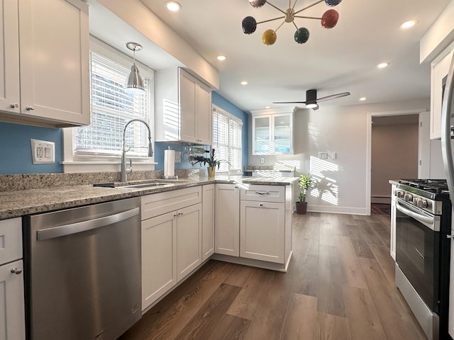 kitchen with recessed lighting, a sink, appliances with stainless steel finishes, light stone countertops, and dark wood finished floors