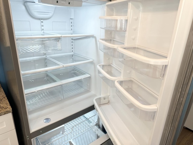 interior details with stone counters, refrigerator, and white cabinets