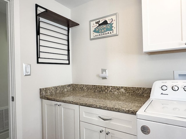 washroom with visible vents, washer / clothes dryer, and cabinet space