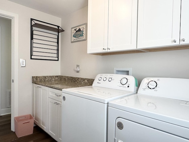 clothes washing area featuring visible vents, washer and clothes dryer, dark wood finished floors, and cabinet space