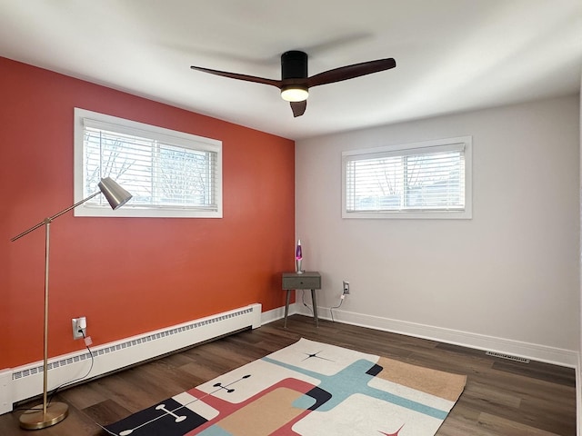 spare room with a wealth of natural light, a baseboard radiator, baseboards, and dark wood-style floors