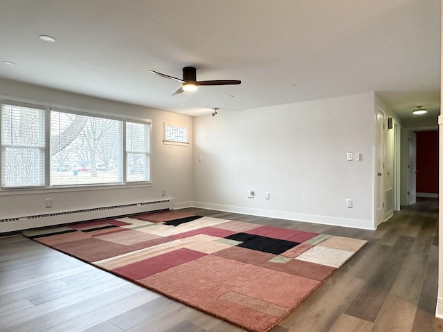 unfurnished room featuring a ceiling fan, a baseboard radiator, baseboards, and wood finished floors