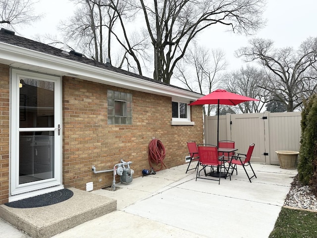 view of patio with a gate, fence, and outdoor dining space