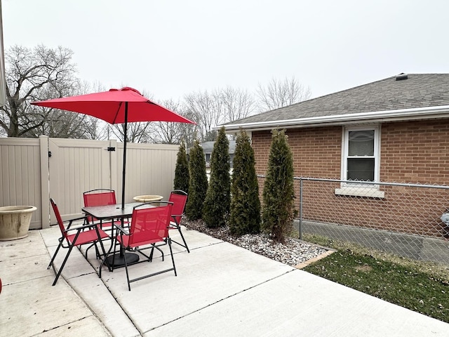 view of patio featuring a gate, fence, and outdoor dining area