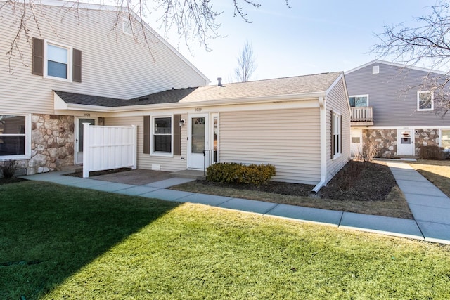 view of front of home with roof with shingles and a front lawn