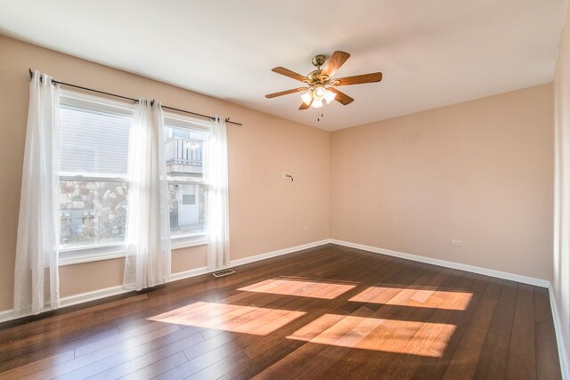 spare room featuring dark wood-style flooring, ceiling fan, and baseboards