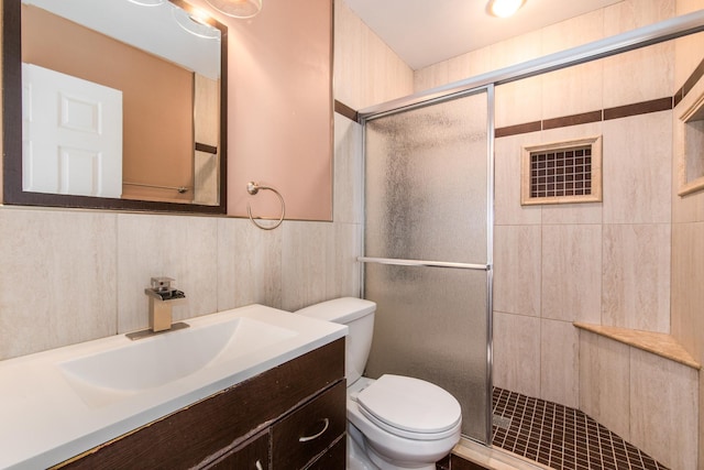 bathroom with toilet, a shower stall, and vanity