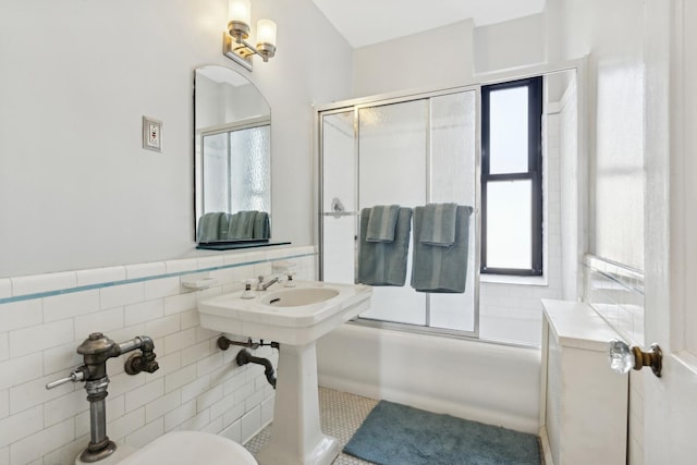 full bathroom featuring wainscoting, combined bath / shower with glass door, and tile walls