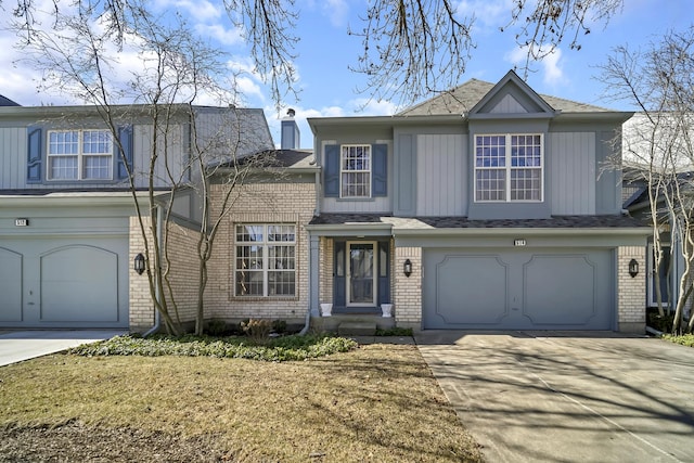 traditional-style home with concrete driveway, a garage, brick siding, and board and batten siding