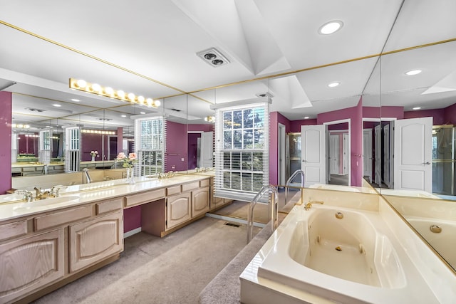 bathroom with a tub with jets, visible vents, double vanity, and a sink
