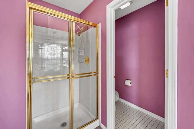 bathroom with a stall shower, toilet, baseboards, and tile patterned floors