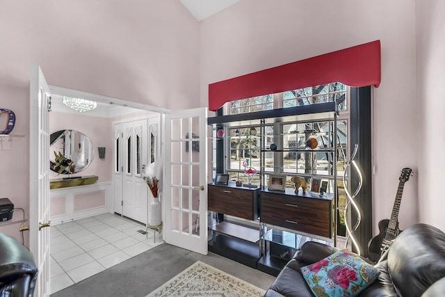 interior space with tile patterned floors, french doors, and a towering ceiling