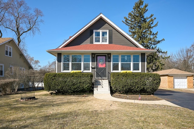 bungalow-style home featuring a garage, an outdoor structure, and a front yard